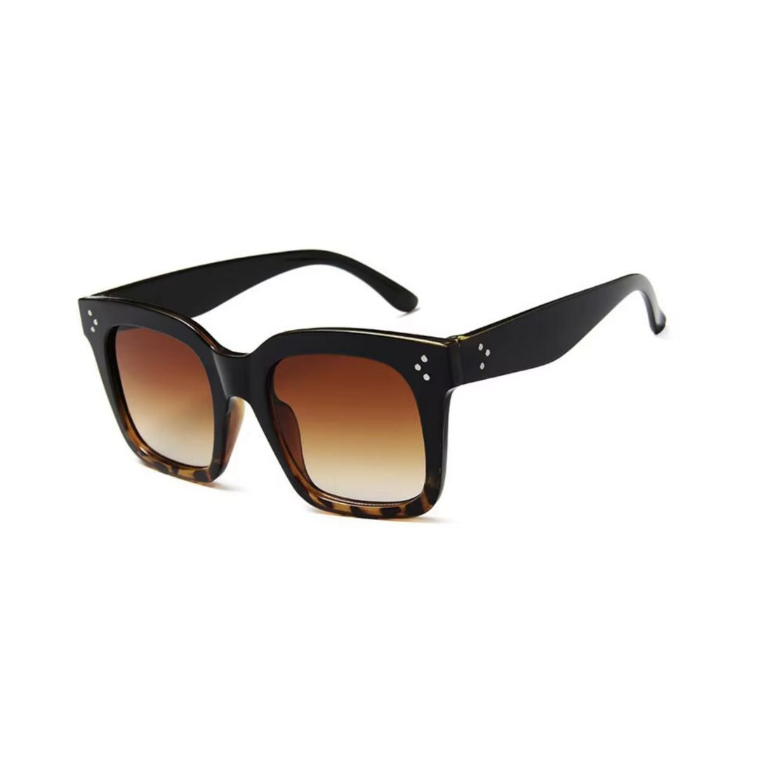 Oversized square sunglasses with a black-to-tortoiseshell frame, gradient brown lenses, and subtle metal rivet details on the corners for a chic and bold look.