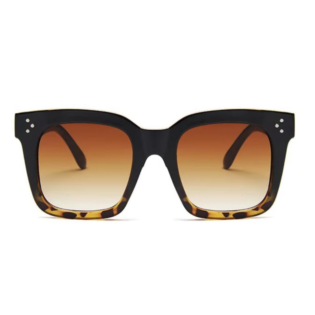 Oversized square sunglasses with a black-to-tortoiseshell frame, gradient brown lenses, and subtle metal rivet details on the corners for a chic and bold look.